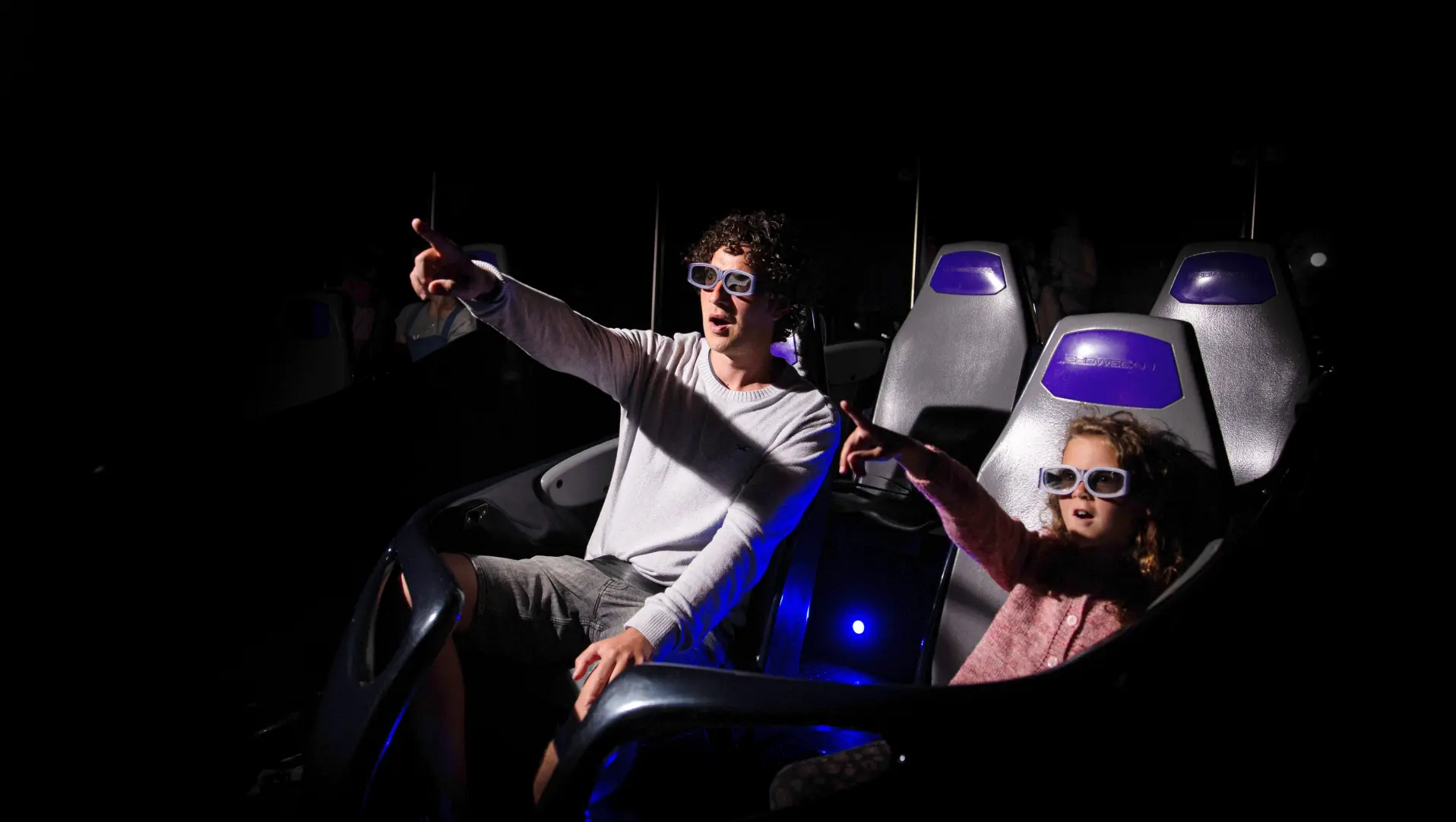 A man and a girl watch the 5D Cinema screen with glasses on
