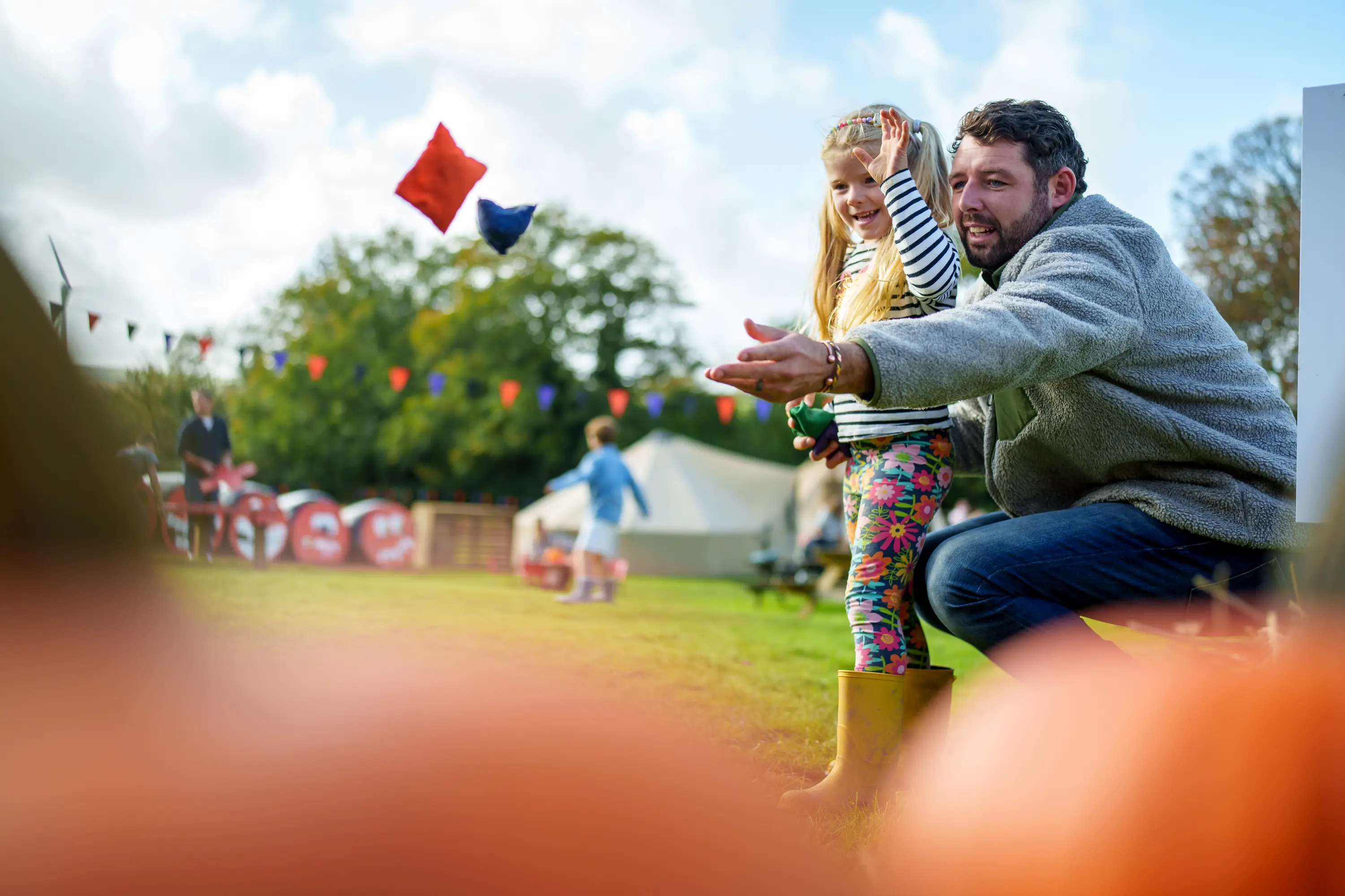 A man and girl throwing bean bags at Pumpkin Fest