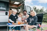 A family sitting outside their caravan at the camping and glamping site at Camel Creek