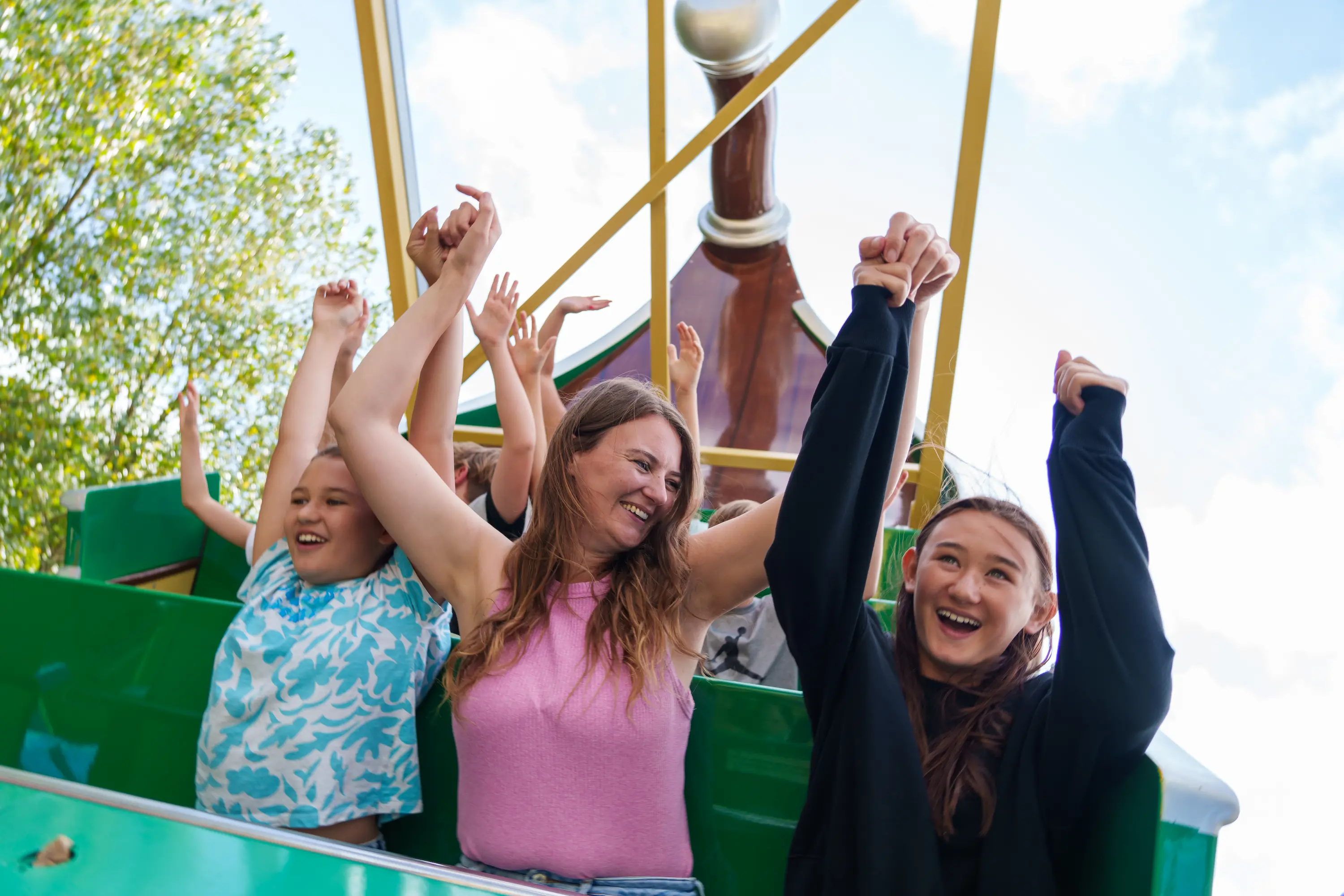 Woman and girls with hands up in the air on Pirate of The 7 Seas ride