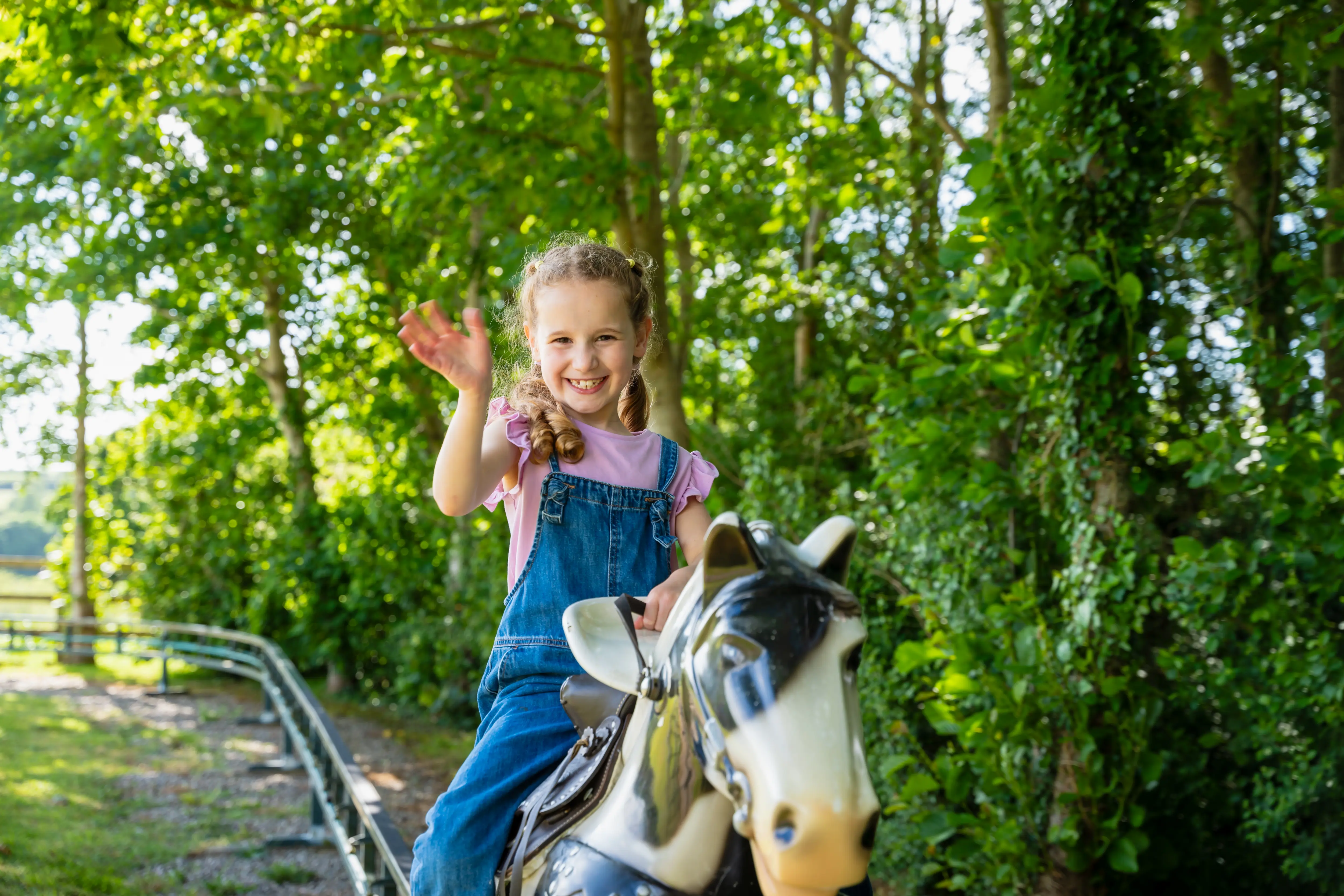 Girl waving to camera whilst on pony express ride