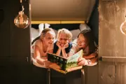 A woman reading a book to her children inside the glamping bell tent 