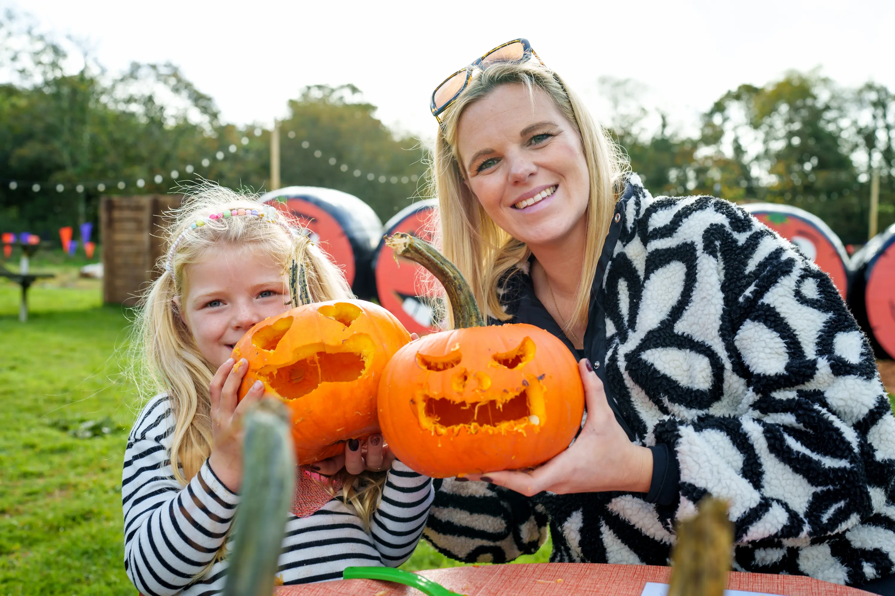A woman and girl smiling with their carved pumpkins